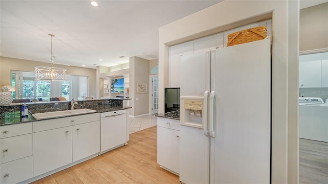 kitchen featuring white appliances, a sink, white cabinets, light wood-type flooring, and washer / clothes dryer