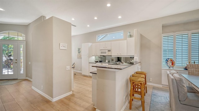 kitchen with white cabinetry, plenty of natural light, light hardwood / wood-style floors, and kitchen peninsula