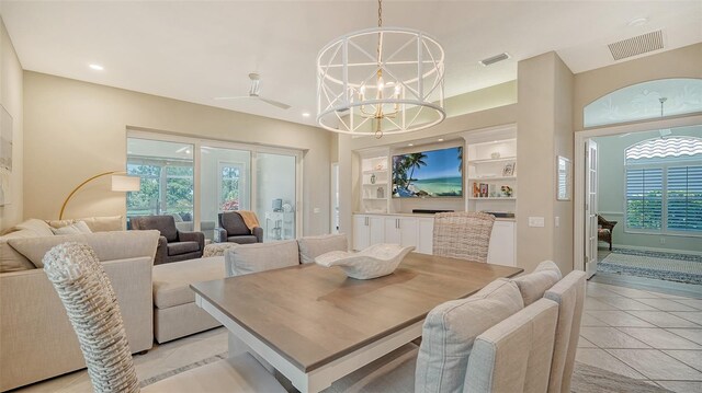 dining space with ceiling fan with notable chandelier, light tile patterned floors, and built in features