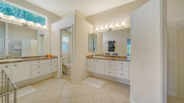 bathroom featuring a healthy amount of sunlight, vanity, toilet, and tile patterned flooring