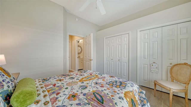 bedroom featuring vaulted ceiling, ceiling fan, light wood-type flooring, and two closets