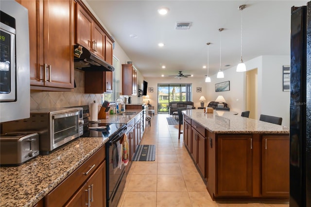 kitchen featuring pendant lighting, sink, backsplash, black electric range, and light stone countertops