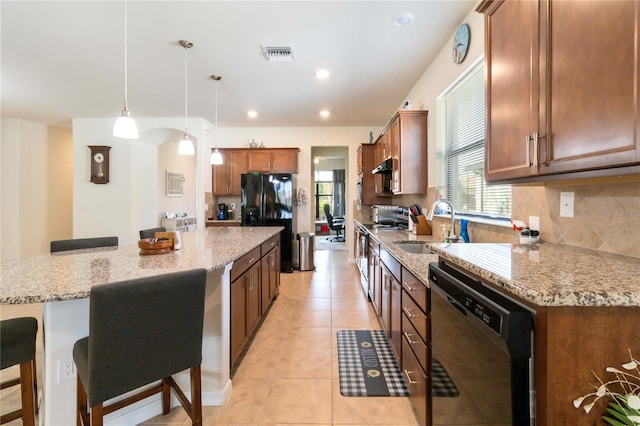 kitchen featuring pendant lighting, sink, a kitchen breakfast bar, black appliances, and light stone countertops