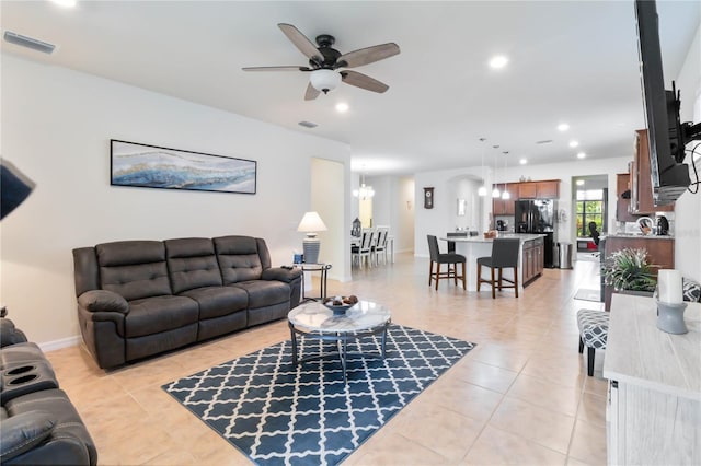 tiled living room featuring ceiling fan with notable chandelier