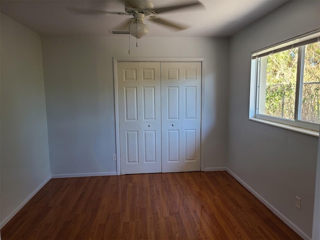 unfurnished bedroom featuring dark wood-type flooring, a closet, and ceiling fan