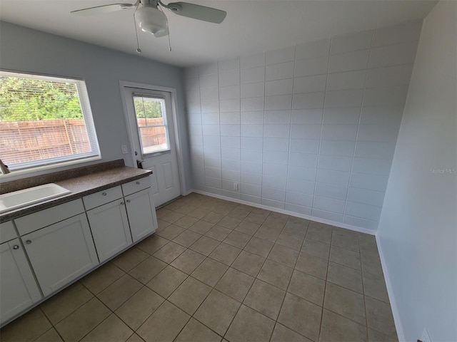 kitchen featuring white cabinetry, sink, tile walls, and ceiling fan