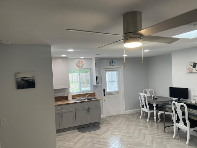 kitchen featuring gray cabinetry, sink, light parquet flooring, and ceiling fan