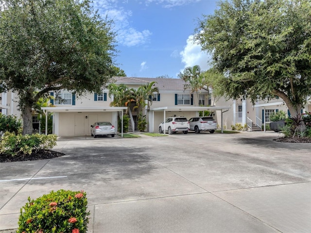 multi unit property with covered and uncovered parking, stairs, and stucco siding