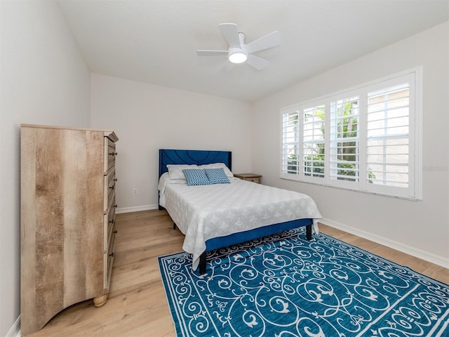 bedroom featuring ceiling fan, baseboards, and light wood-style floors