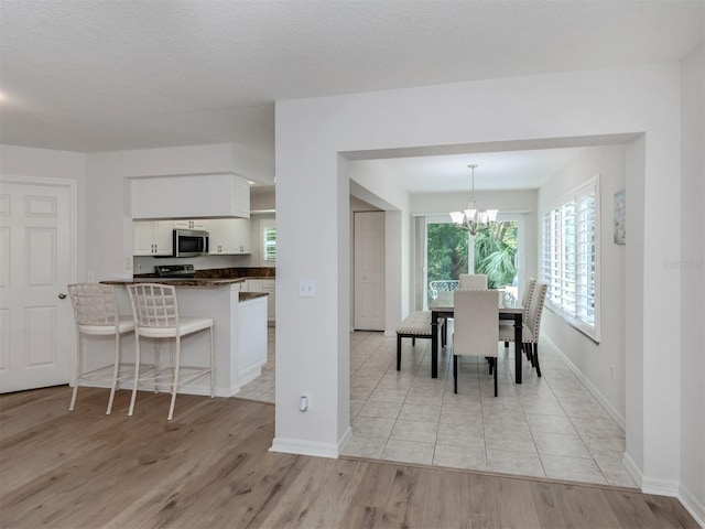 dining space with baseboards, light wood-style floors, and a chandelier