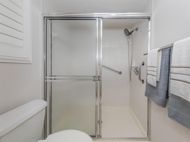 bathroom featuring toilet, an enclosed shower, and a textured ceiling