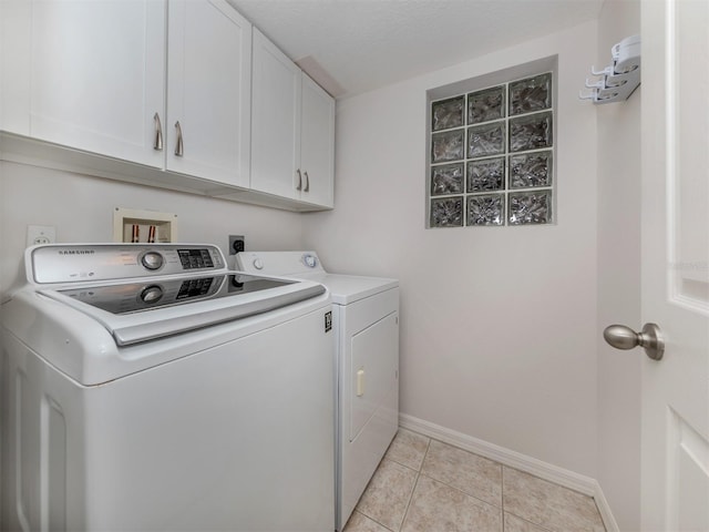 clothes washing area with light tile patterned floors, a textured ceiling, cabinets, and washing machine and clothes dryer