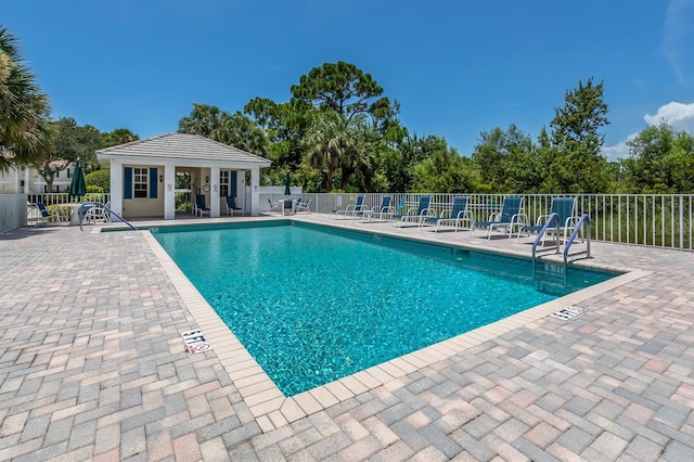 pool featuring a patio, fence, and an outbuilding