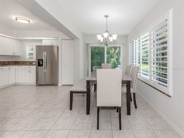 dining space with light tile patterned floors, baseboards, and a notable chandelier