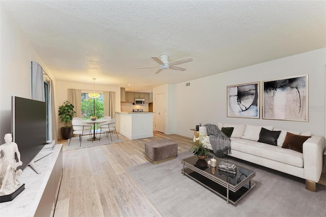 living room featuring hardwood / wood-style flooring, ceiling fan, and a textured ceiling