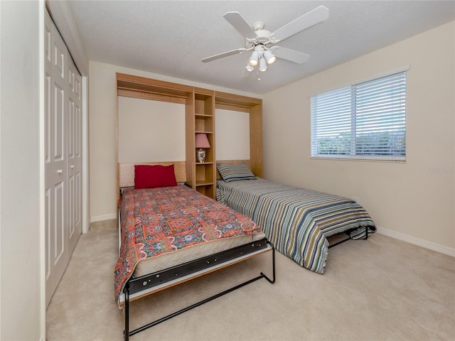 carpeted bedroom featuring ceiling fan and a closet