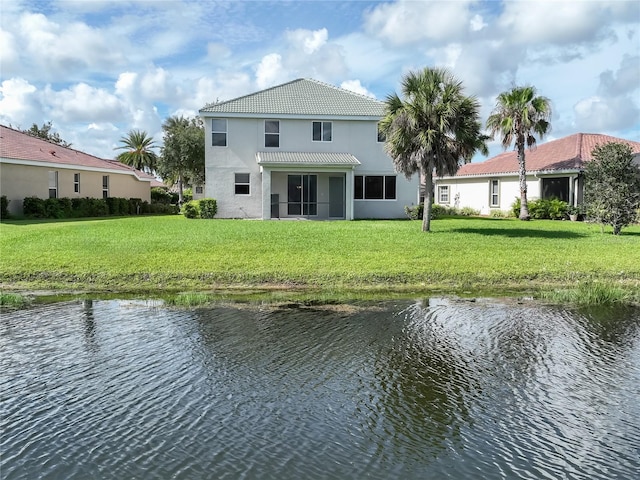 rear view of house featuring a lawn and a water view