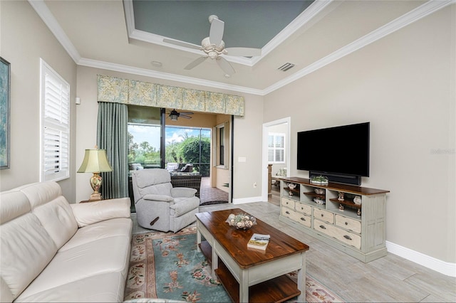 living room with ornamental molding, light hardwood / wood-style flooring, and a tray ceiling