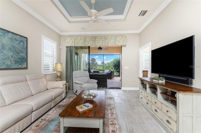 living room with a healthy amount of sunlight, a tray ceiling, and crown molding