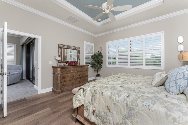 bedroom featuring hardwood / wood-style floors, ceiling fan, a raised ceiling, and crown molding