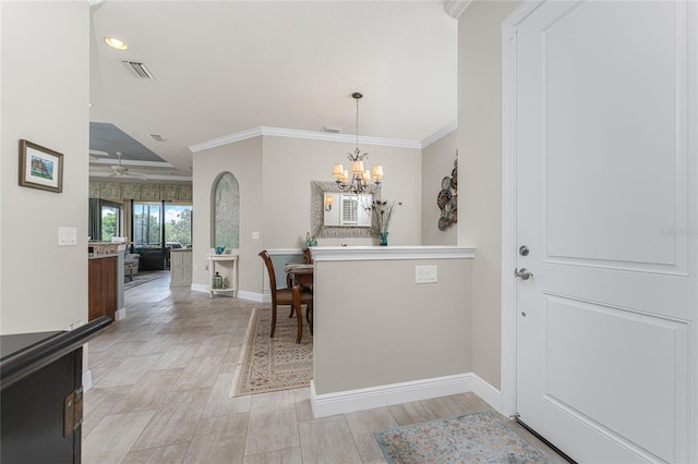 foyer featuring ceiling fan with notable chandelier, light wood-type flooring, and crown molding