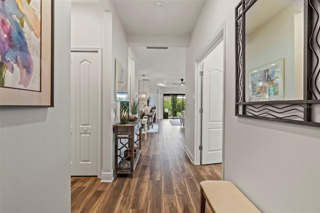 hallway with visible vents, dark wood-type flooring, and baseboards