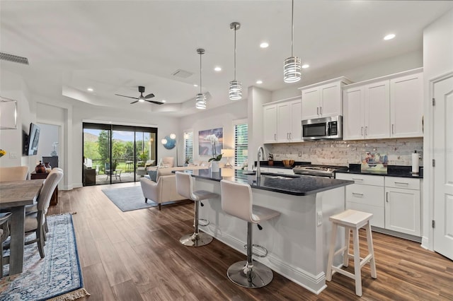 kitchen with white cabinetry, a kitchen island with sink, sink, and ceiling fan