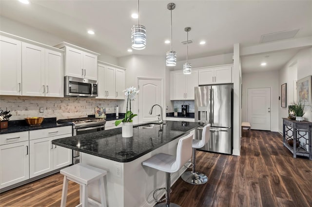 kitchen with a sink, a kitchen breakfast bar, dark wood finished floors, stainless steel appliances, and white cabinets