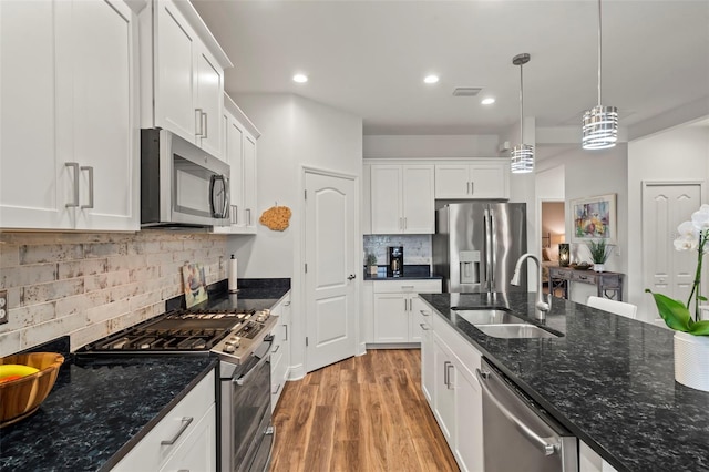 kitchen featuring appliances with stainless steel finishes, white cabinetry, hanging light fixtures, and sink