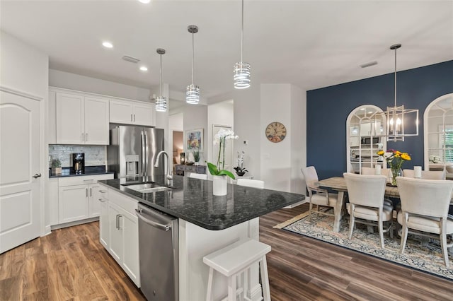 kitchen with sink, stainless steel appliances, backsplash, a kitchen island with sink, and white cabinets