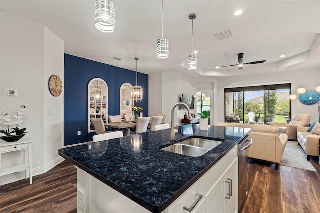 kitchen with a sink, open floor plan, recessed lighting, a raised ceiling, and dark wood-style flooring