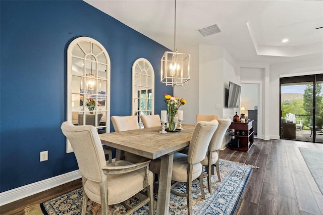 dining space featuring dark wood-type flooring and an inviting chandelier