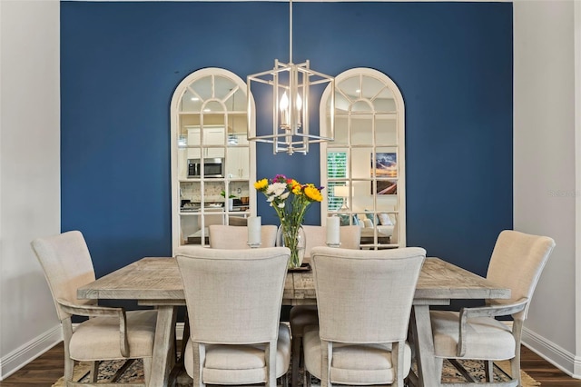 dining area featuring baseboards, a notable chandelier, and dark wood-style flooring