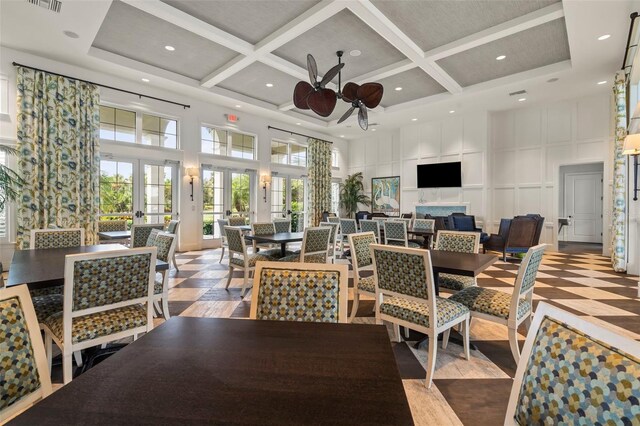 dining room featuring french doors, beam ceiling, coffered ceiling, and a high ceiling