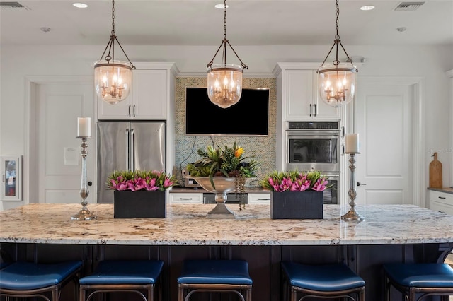 kitchen with pendant lighting, a large island, white cabinets, and appliances with stainless steel finishes