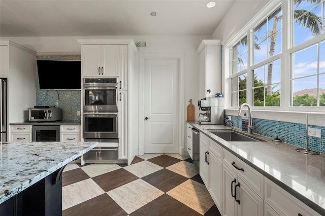 kitchen featuring beverage cooler, a sink, stainless steel appliances, white cabinets, and backsplash