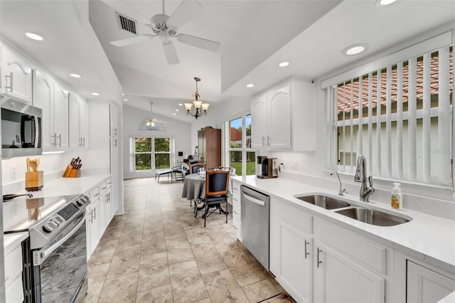 kitchen with hanging light fixtures, sink, vaulted ceiling, appliances with stainless steel finishes, and white cabinetry