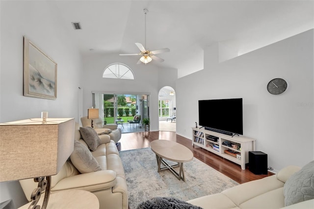 living room featuring hardwood / wood-style flooring, ceiling fan, and a towering ceiling