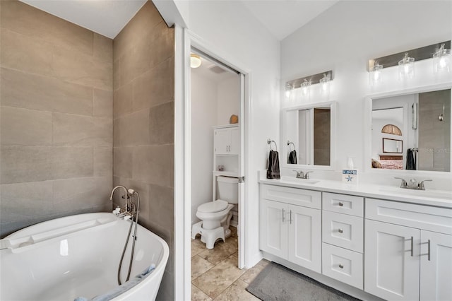 bathroom with vanity, toilet, a tub, and tile walls