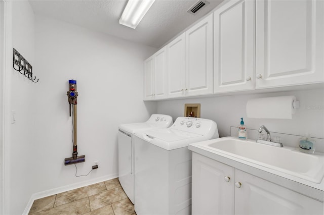 laundry room with cabinets, a textured ceiling, sink, light tile patterned floors, and washing machine and clothes dryer