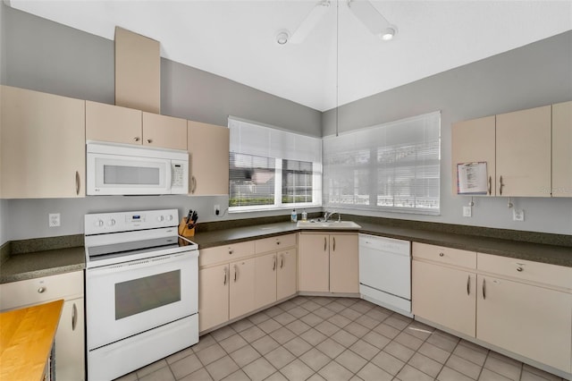 kitchen featuring cream cabinetry, white appliances, sink, and light tile patterned floors