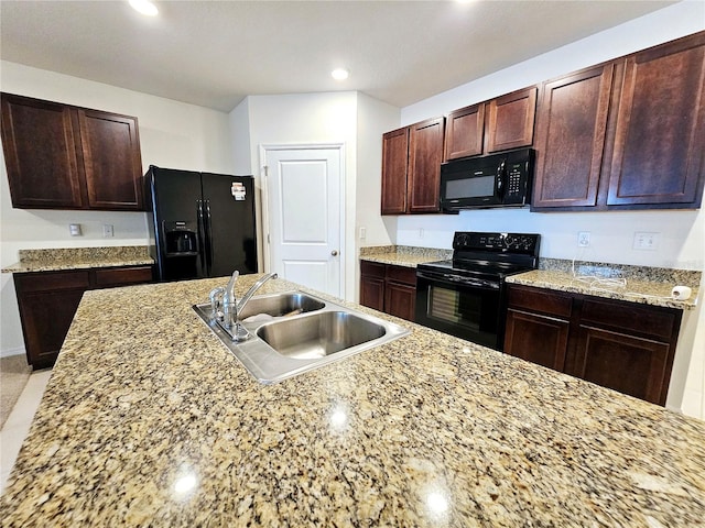 kitchen with sink, light stone counters, and black appliances