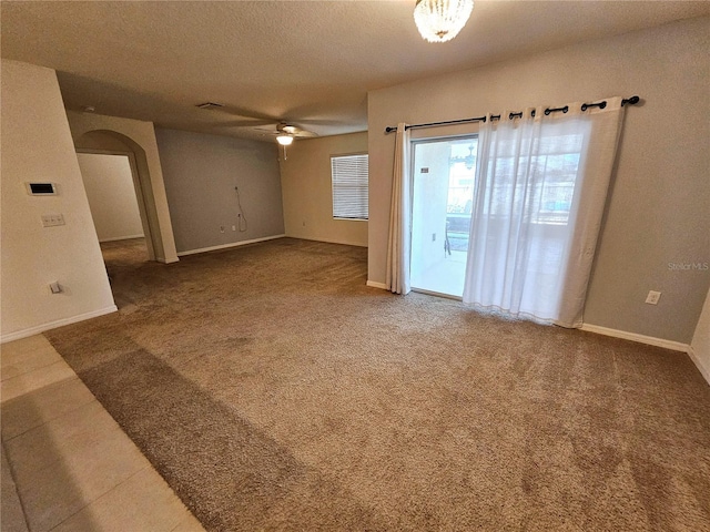 spare room featuring carpet, a textured ceiling, and ceiling fan with notable chandelier