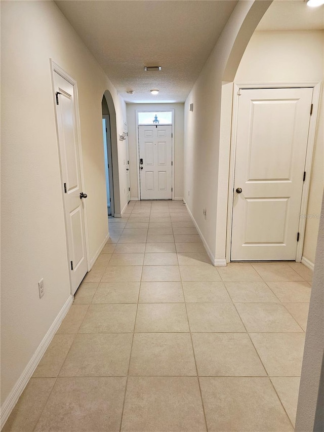 corridor featuring light tile patterned floors and a textured ceiling