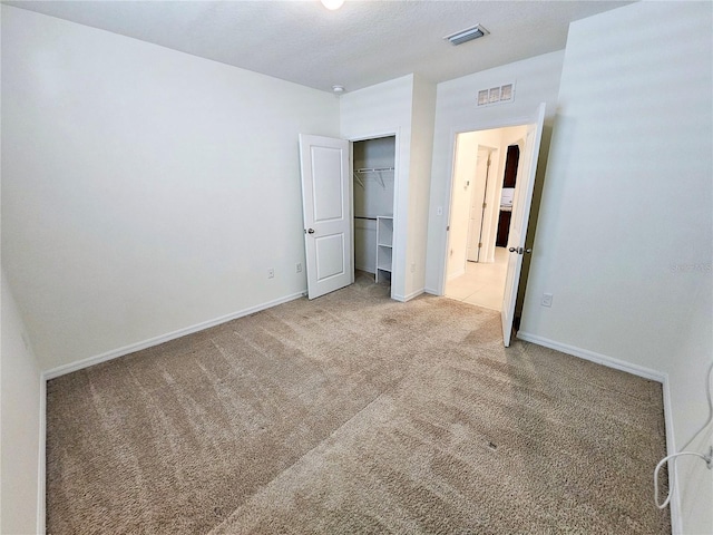 unfurnished bedroom with light carpet and a closet