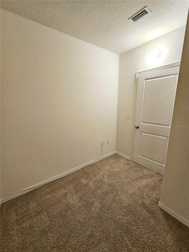 carpeted empty room with a textured ceiling