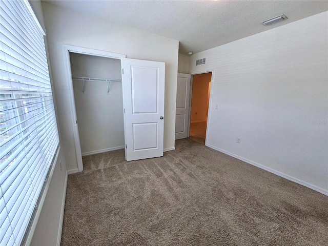 unfurnished bedroom with dark colored carpet and a closet