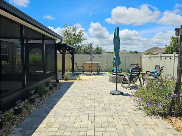 view of patio featuring a sunroom and a fire pit