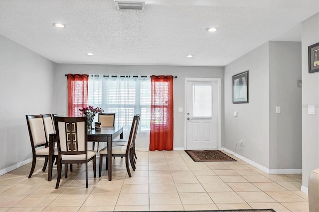 dining space with a wealth of natural light, light tile flooring, and a textured ceiling