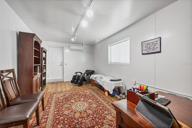 bedroom featuring track lighting, light hardwood / wood-style floors, and an AC wall unit